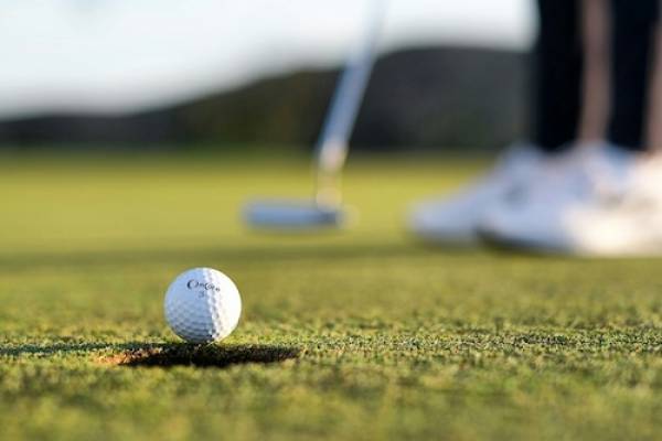 Man hitting golf ball into hole